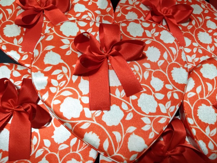 Corazón para bombones con flores blancas fondo rojo