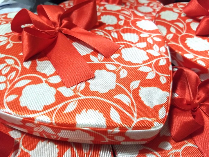 Corazón para bombones con flores blancas fondo rojo